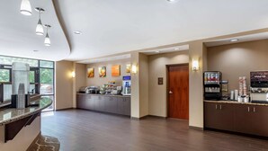 Un hall d’hôtel moderne avec un comptoir d’accueil, un espace café et une vue sur l’extérieur.