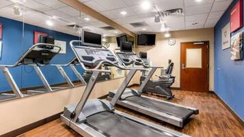 A gym with treadmills, exercise bikes, and a mirrored wall.