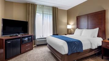 A hotel room with a bed, a TV, a desk, and a lamp.