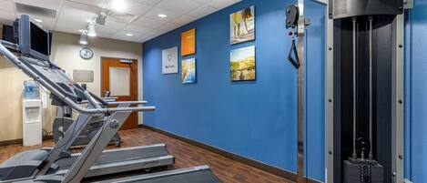 Un gimnasio con cintas de correr, máquinas de pesas y decoración inspiradora en las paredes.