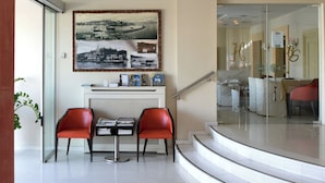 Un hall d’hôtel moderne avec un escalier en colimaçon, un comptoir d’accueil et des chaises rouges.