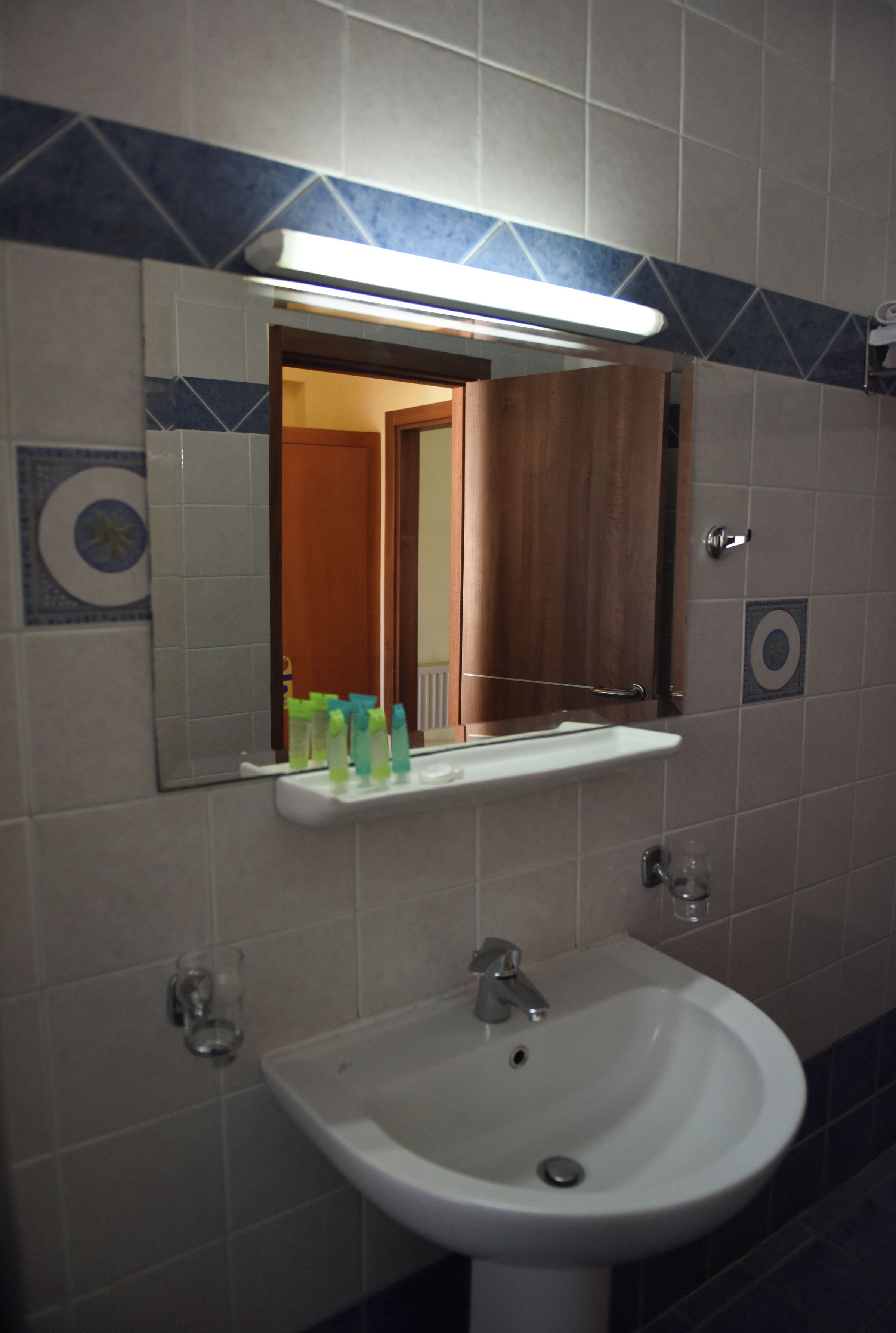 A bathroom with a sink, mirror, and a shelf with toiletries.