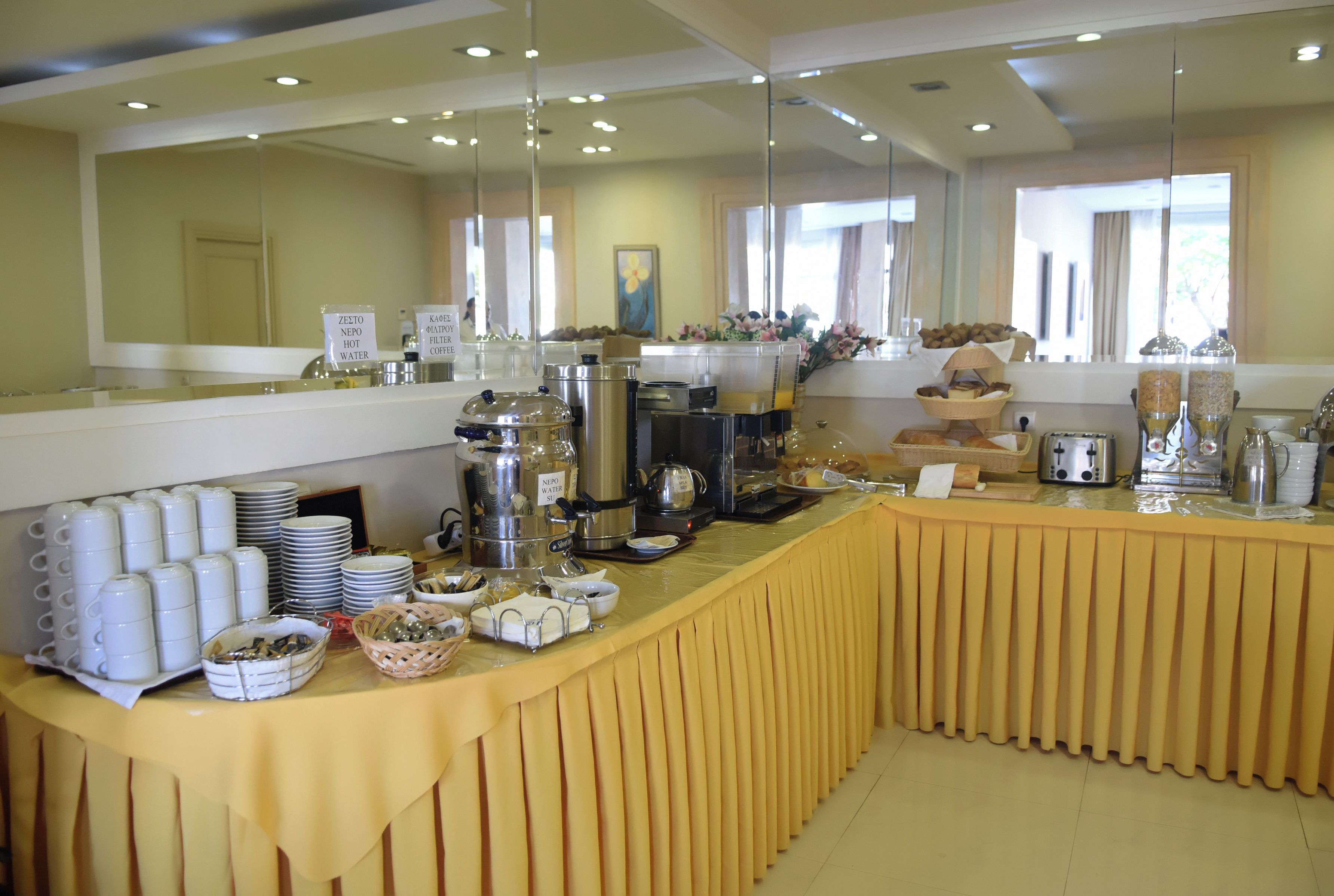 Montaje de bufé con diversos recipientes de comida y bebida, incluyendo café y agua caliente.