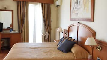 A hotel room with a large bed, bedside tables, a desk, a chair, a television, and a painting on the wall.