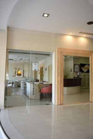 A hotel lobby with a reception desk, a dining area with chairs, and a glass partition. - Blue Sea (Lesvos)