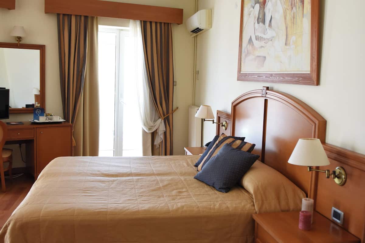 Une chambre d’hôtel avec un grand lit, des tables de chevet, un bureau, une chaise, une télévision et un tableau au mur.