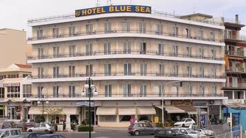 Un hôtel à plusieurs étages, appelé «
Hôtel Blue Sea
», doté d’une façade incurvée, de balcons et d’un espace de stationnement à l’avant.