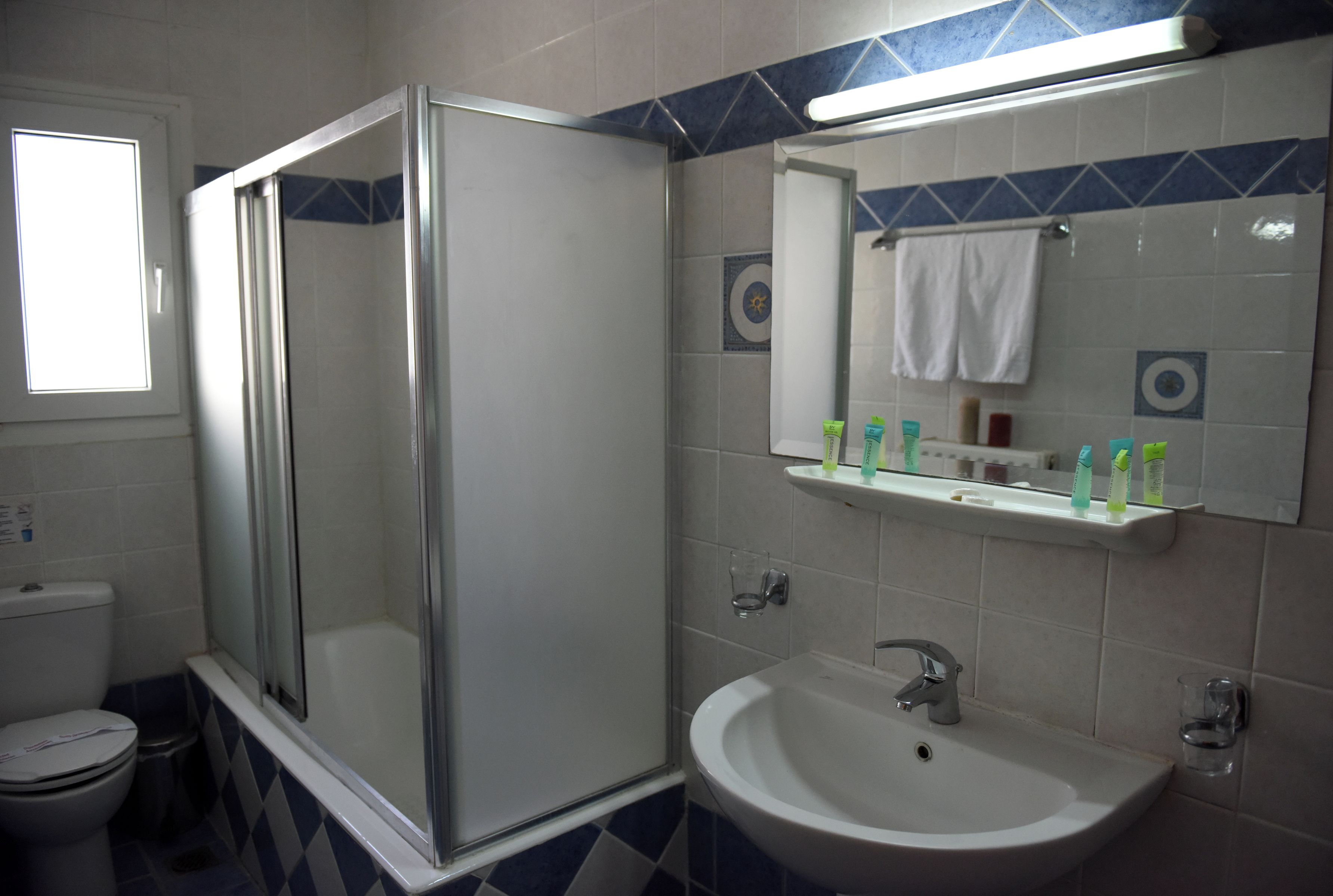 A bathroom with a glass-enclosed shower, a sink, and a mirror above it.