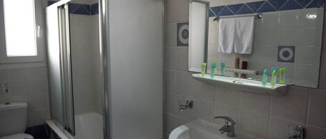 A bathroom with a glass-enclosed shower, a sink, and a mirror above it.
