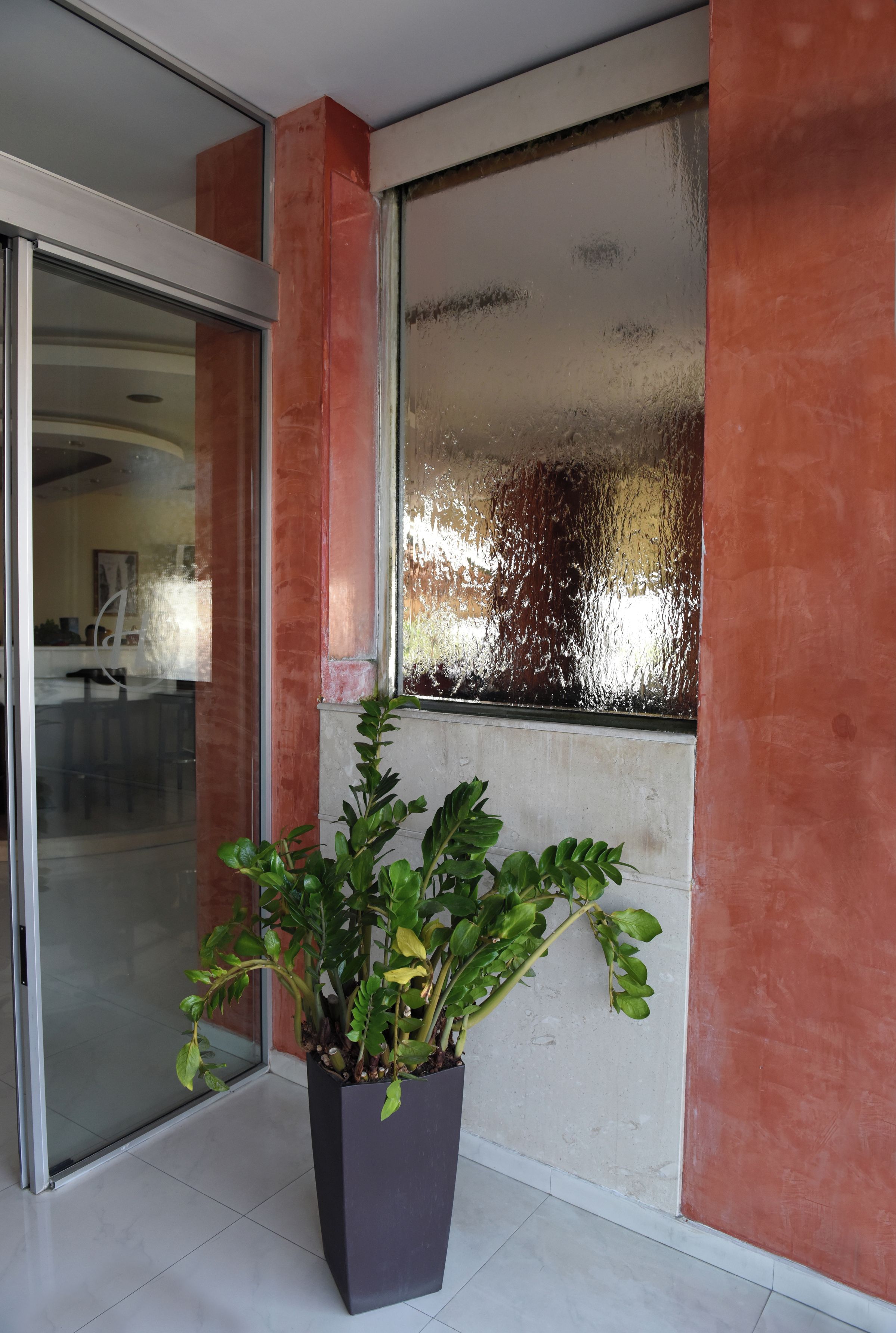 A potted plant near a sliding glass door with a view of a room.