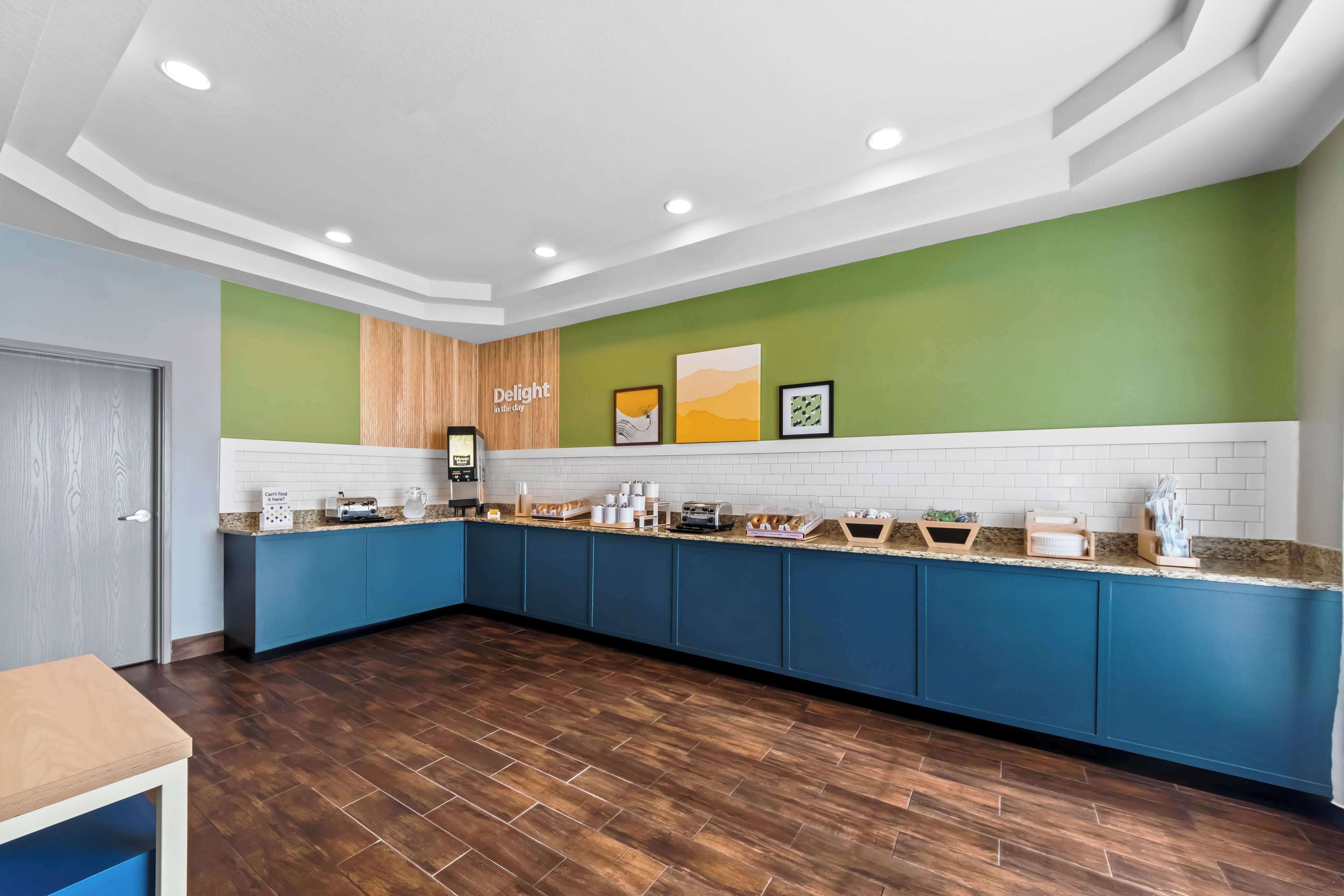 Una cocina moderna con armarios azules, un revestimiento de pared de madera y una encimera blanca con varios electrodomésticos y objetos.