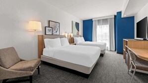 A hotel room with two single beds, a desk, a chair, a lamp, and a television. - Spark by Hilton San Antonio near SeaWorld (San Antonio)