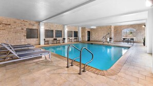 An indoor swimming pool with lounge chairs and a stone wall. - Spark by Hilton San Antonio near SeaWorld (San Antonio)