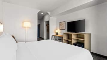 Une chambre d’hôtel avec un grand lit, un bureau avec une chaise, une télévision et une lampe.