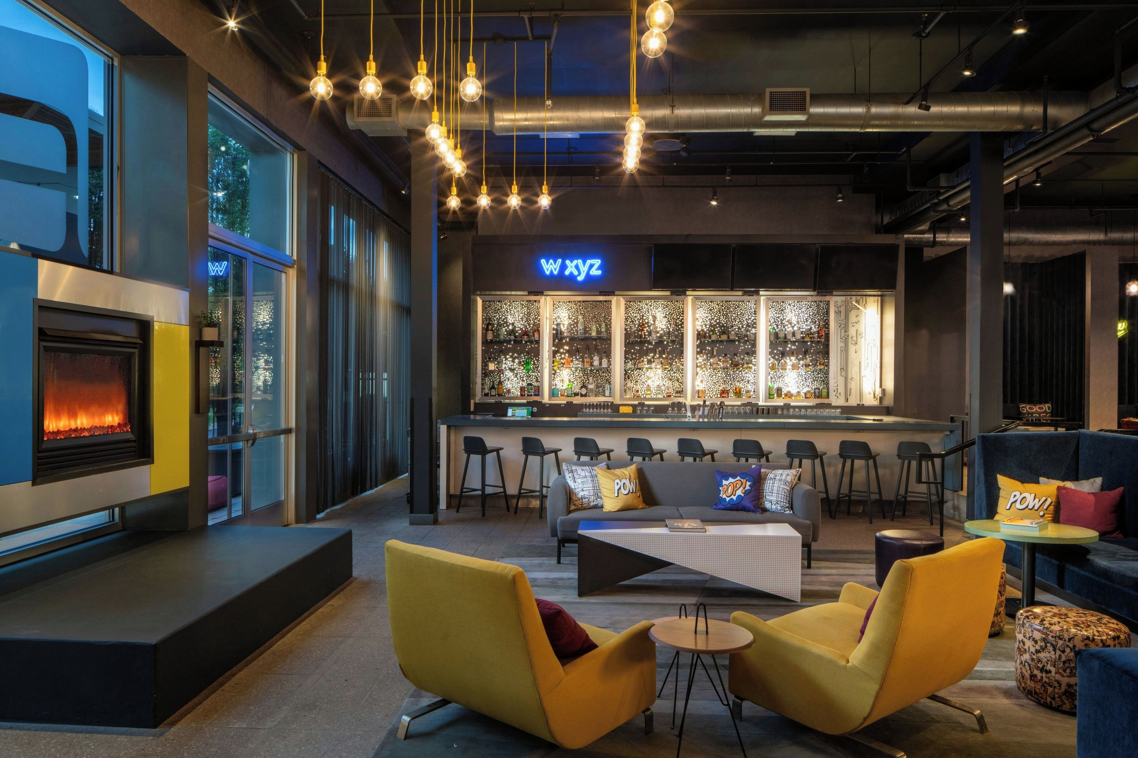 A modern bar area with a neon sign, seating, and a fireplace.