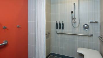Un baño con ducha, inodoro y barra de apoyo.