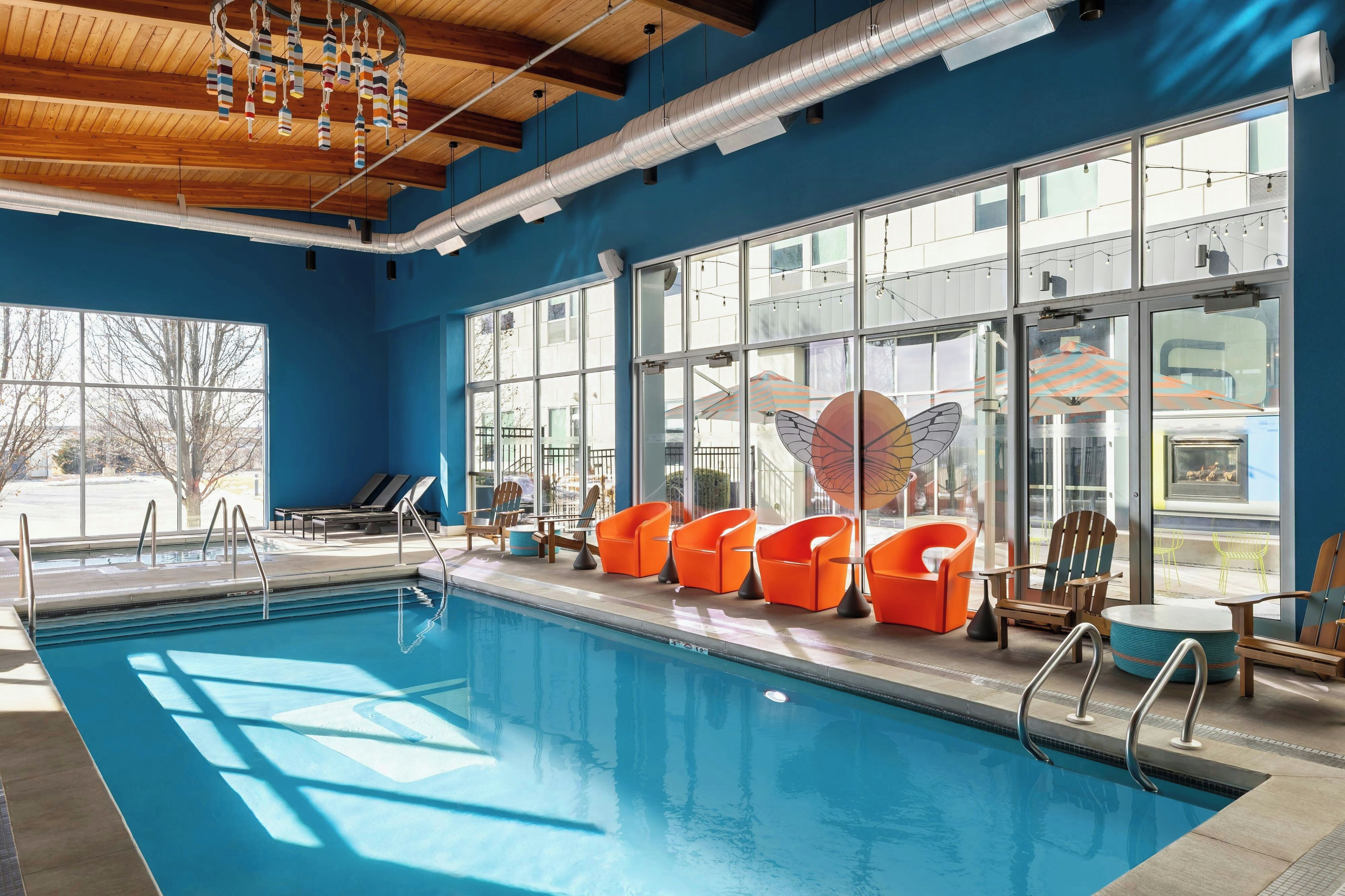 A swimming pool with lounge chairs and a large window overlooking a building.