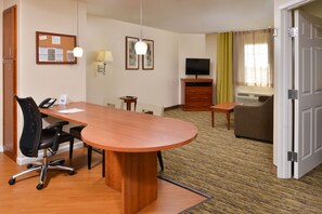 A hotel room with a wooden desk, office chair, a television, a sofa, and a bed. - Candlewood Suites ABILENE by IHG (Abilene)
