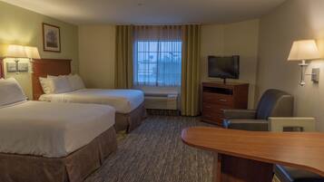A hotel room with two beds, a television, a desk, and a chair.