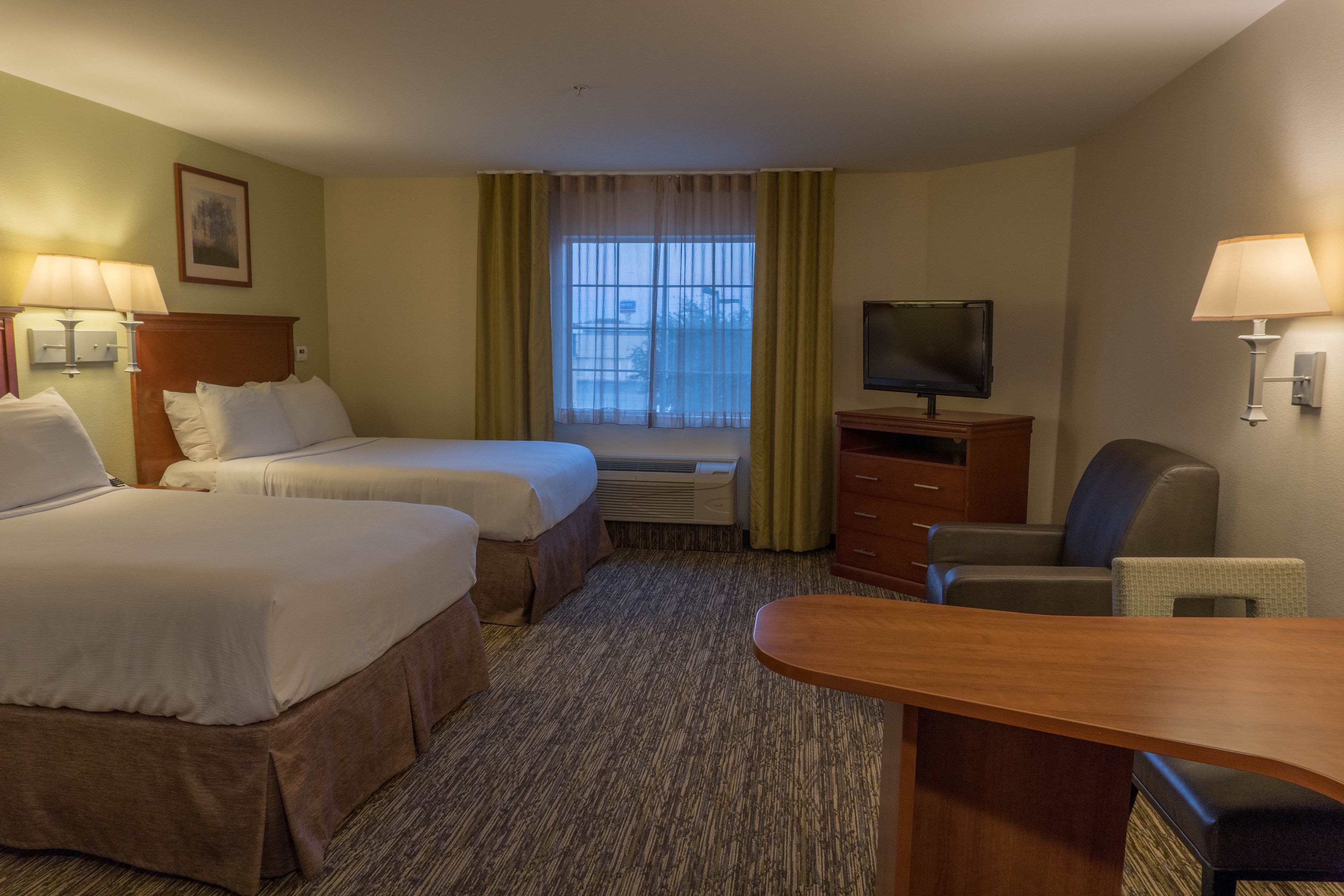 Une chambre d’hôtel avec deux lits, un bureau, une télévision et une chaise.