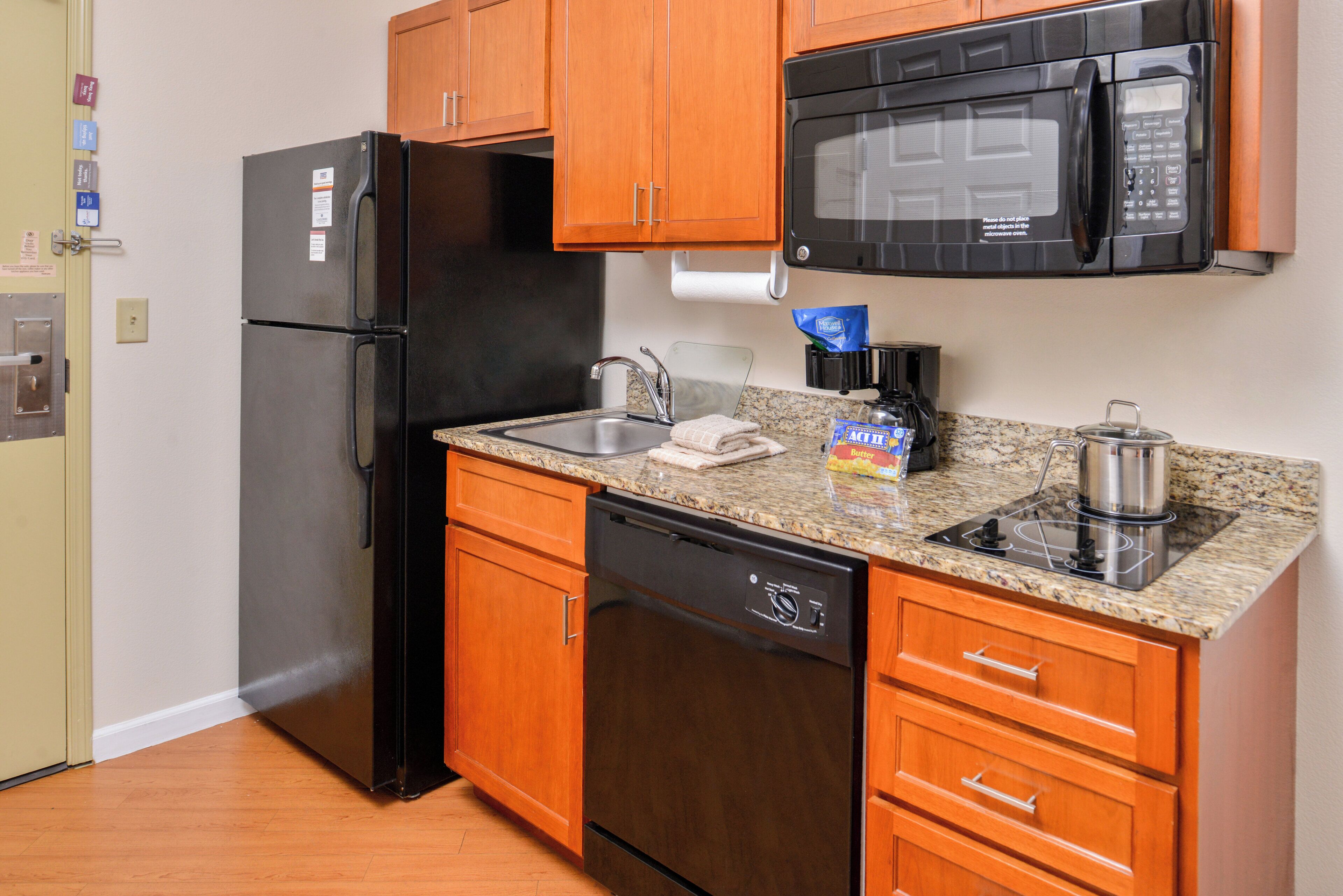 A compact kitchen with a refrigerator, microwave, dishwasher, and a gas stove.
