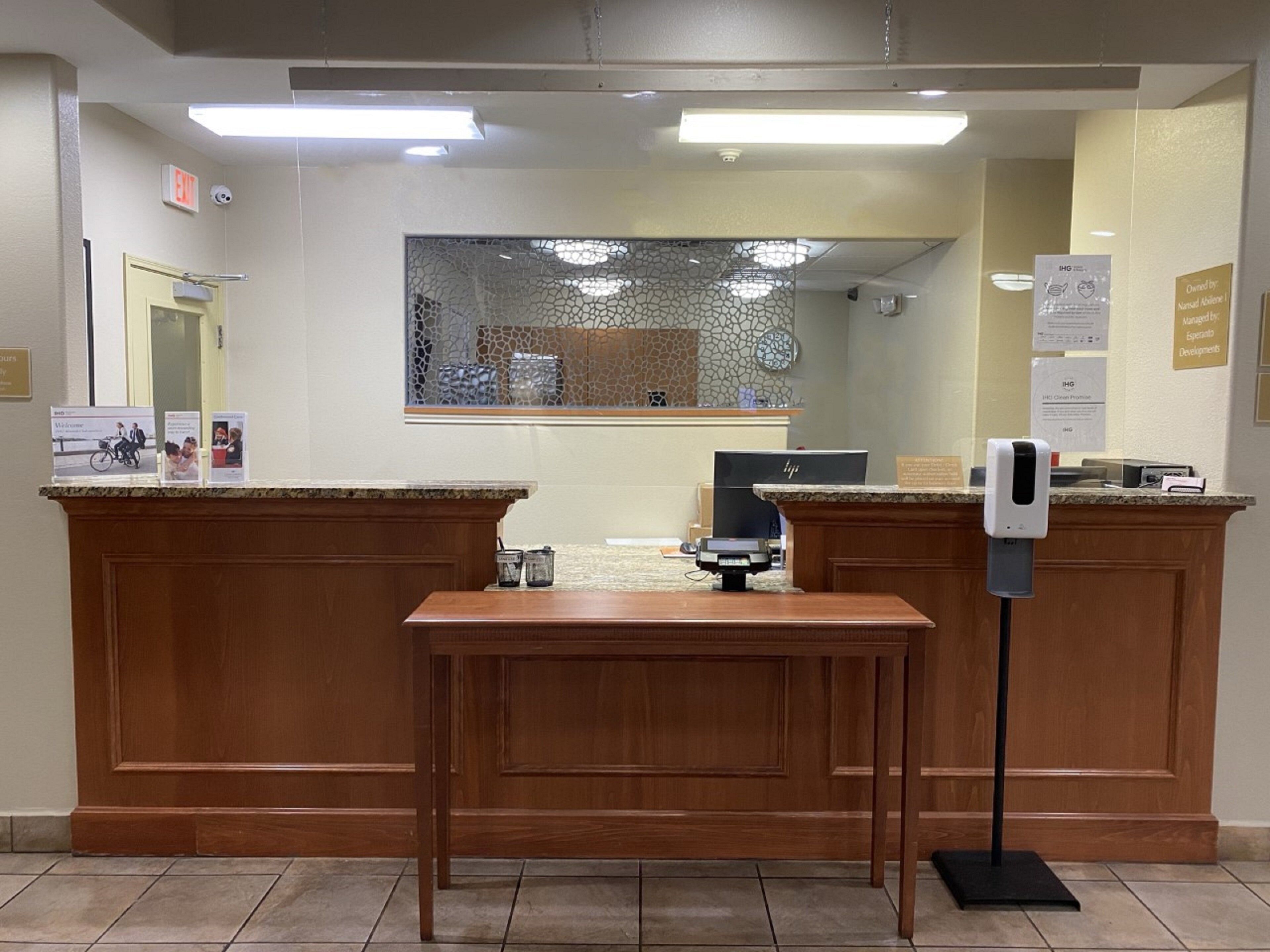 A reception area with wooden reception desks, a computer, and a hand sanitizer dispenser.