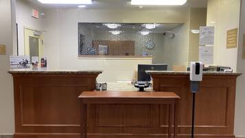 A reception area with wooden reception desks, a computer, and a hand sanitizer dispenser.