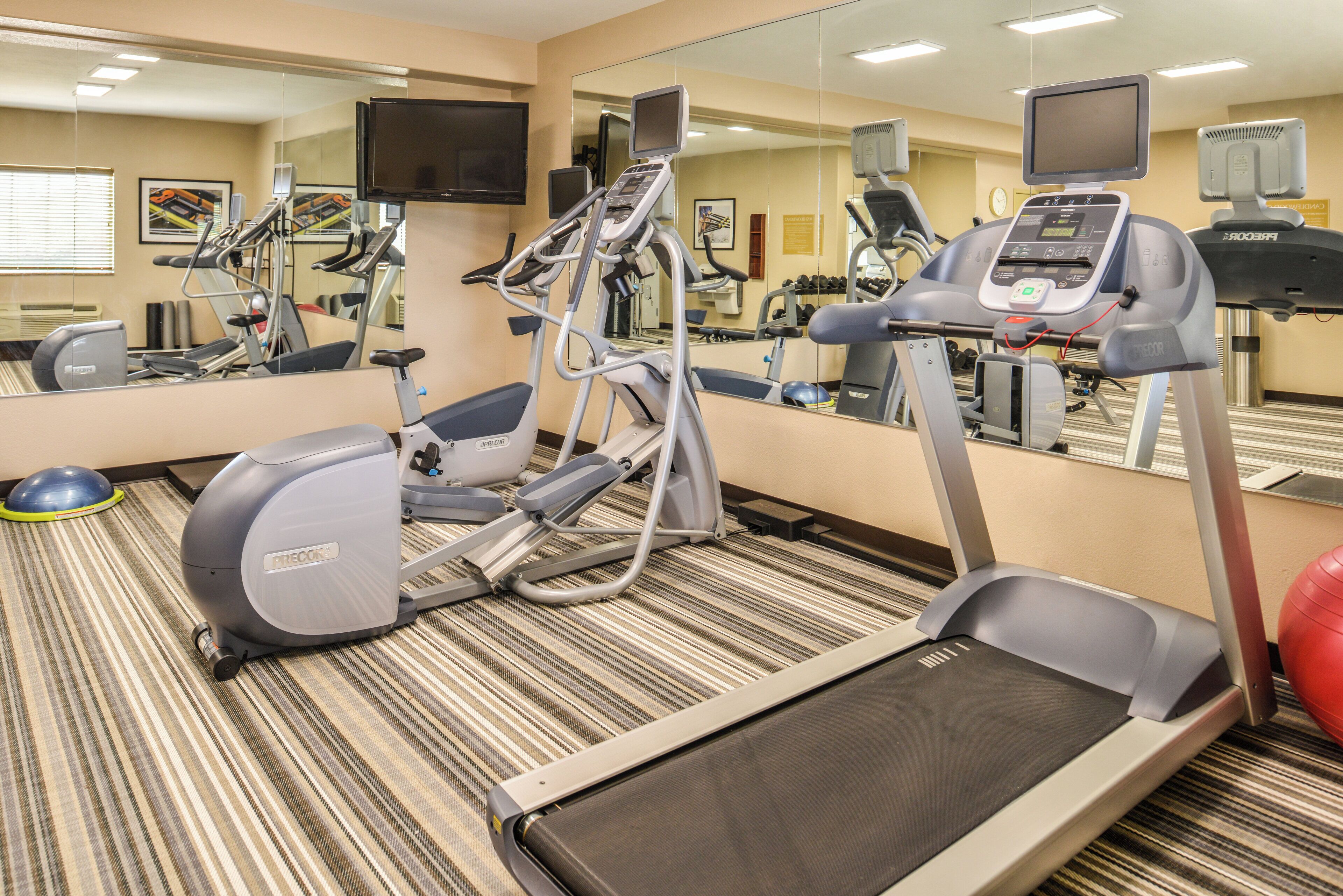 Un gimnasio hotelero con equipos de ejercicio variados, incluyendo cintas de correr, bicicletas estáticas y pesas.