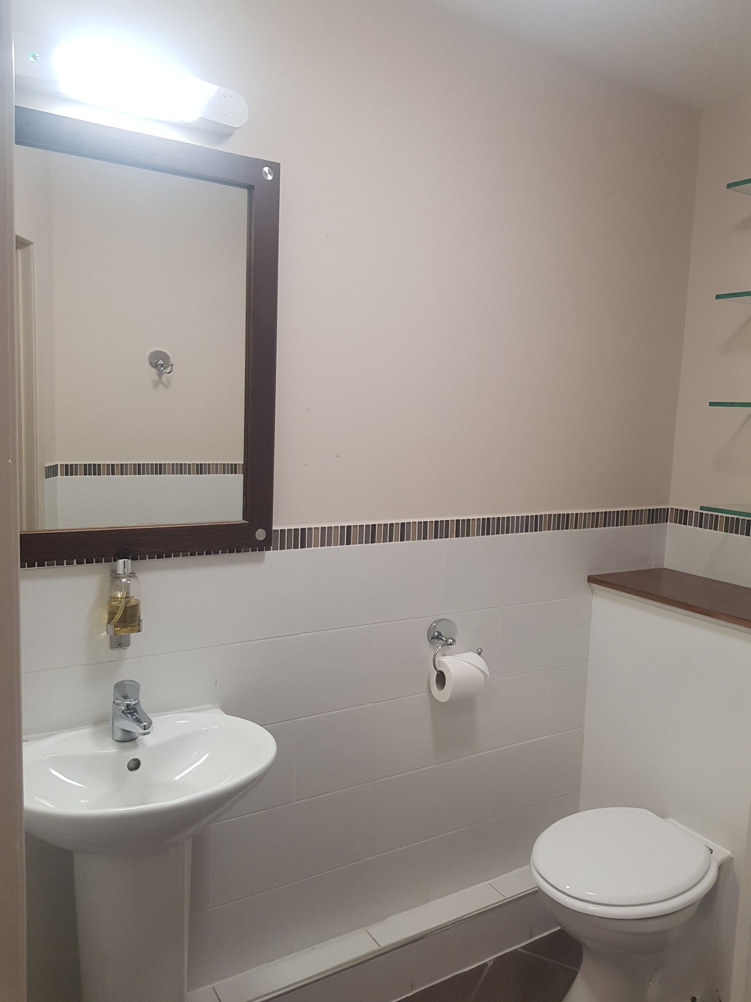 Une salle de bain avec un lavabo blanc, des toilettes et un miroir.