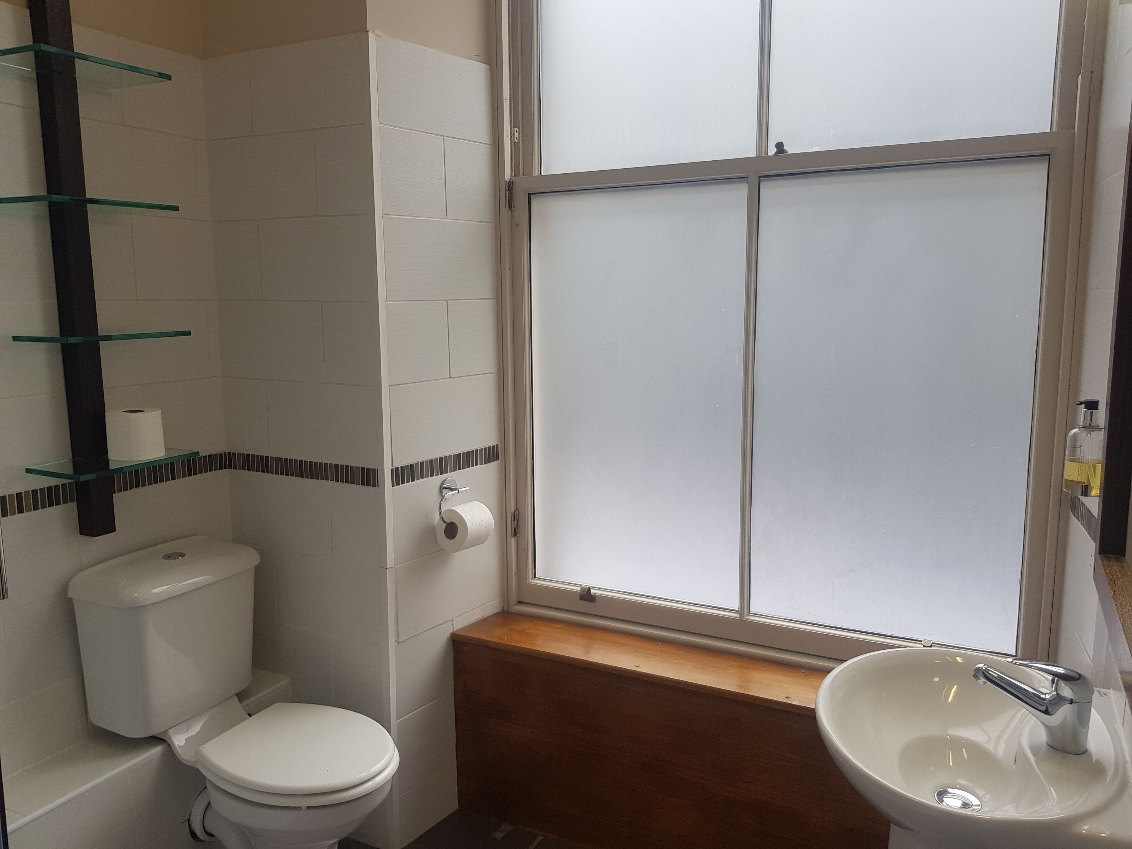 A bathroom with a toilet, a sink, and a window.