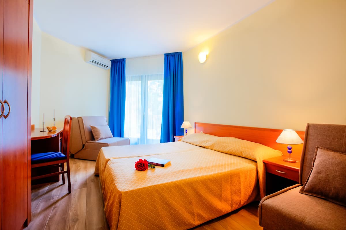 Una habitación de hotel con dos camas, un escritorio con una silla, un sofá y un armario.