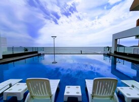 Vista de la piscina con sillas de descanso y una vista despejada del mar.