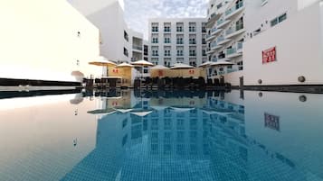 Een buitenzwembad, parasols bij het zwembad en ligstoelen