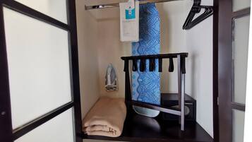 A neatly organized corner with a folded beige towel, a blue patterned towel, a black hanger, and a small black device on a dark wooden shelf.