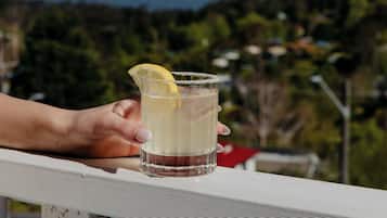 Una mano sostiene un vaso con una rodaja de limón, con vistas a un paisaje pintoresco.