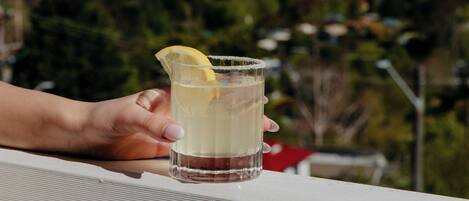 A hand holding a glass with a lemon slice, overlooking a scenic view.