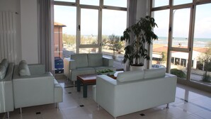 Un salón espacioso con ventanas amplias, un conjunto de sofá, una mesa de centro y una planta en maceta.