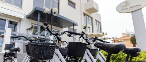 Varias bicicletas estacionadas frente a un edificio con un letrero que dice "HOTEL UNIVERSAL".