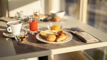 Una mesa de desayuno con croissants, un vaso de zumo de naranja y una taza de café.