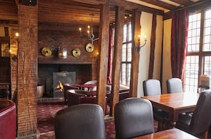 Una habitación acogedora con chimenea de ladrillo, vigas de madera, sillones de cuero y una mesa de comedor.