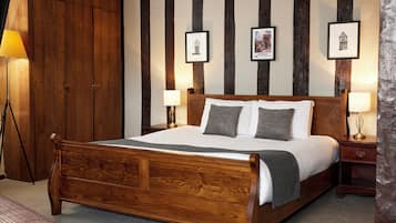 A wooden bed with a white and gray bedding, two bedside lamps, and a framed picture on the wall.