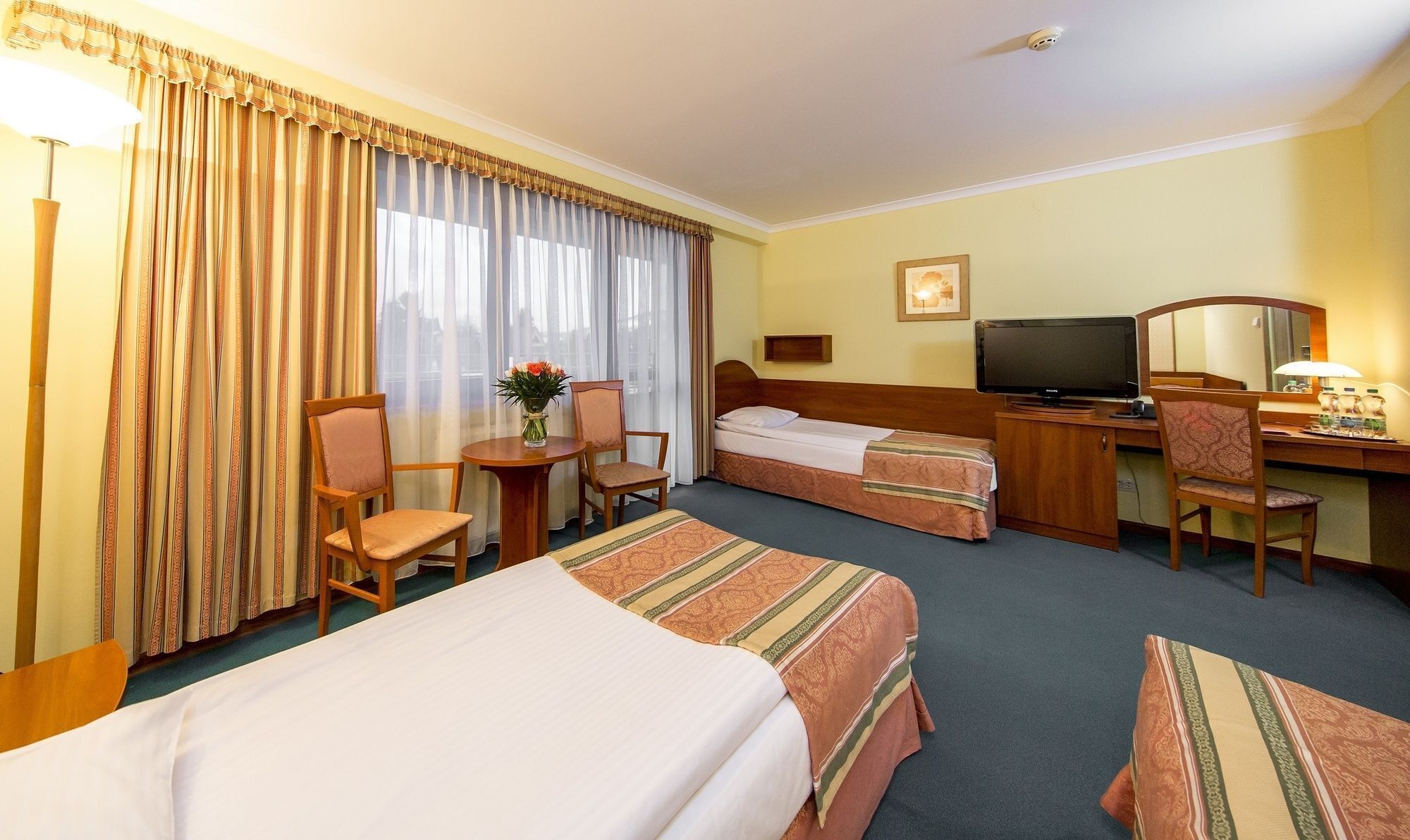 A hotel room with two beds, a desk, a television, and a chair.
