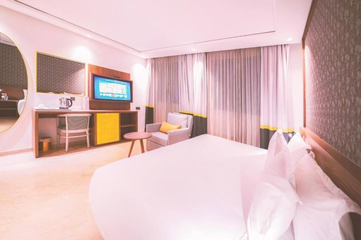 Een hotelkamer met een groot bed, een bureau met een televisie, een stoel en een klein tafeltje.