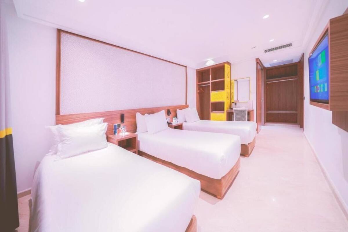 Een hotelkamer met twee bedden, een kledingkast, een televisie en een badkamer.