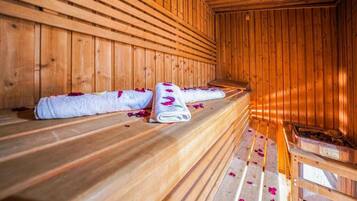 Een sauna met houten banken en banken belegd met handdoeken en rozenblaadjes.