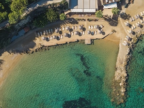 An aerial view of a beach resort with clear waters, sun loungers, and a wooden deck. - Alexandra Beach Resort & Spa (Zakynthos)