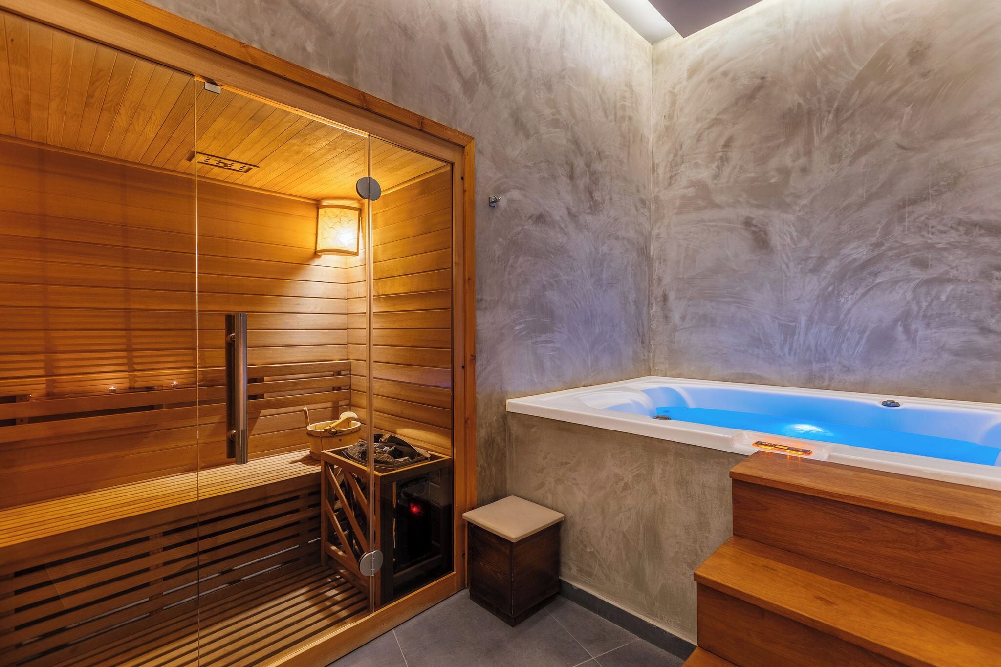 Una sauna con una panca di legno, un piccolo riscaldatore e una porta in vetro.