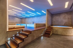 Un bagno moderno con vasca idromassaggio, uno specchio grande e una scala in legno.