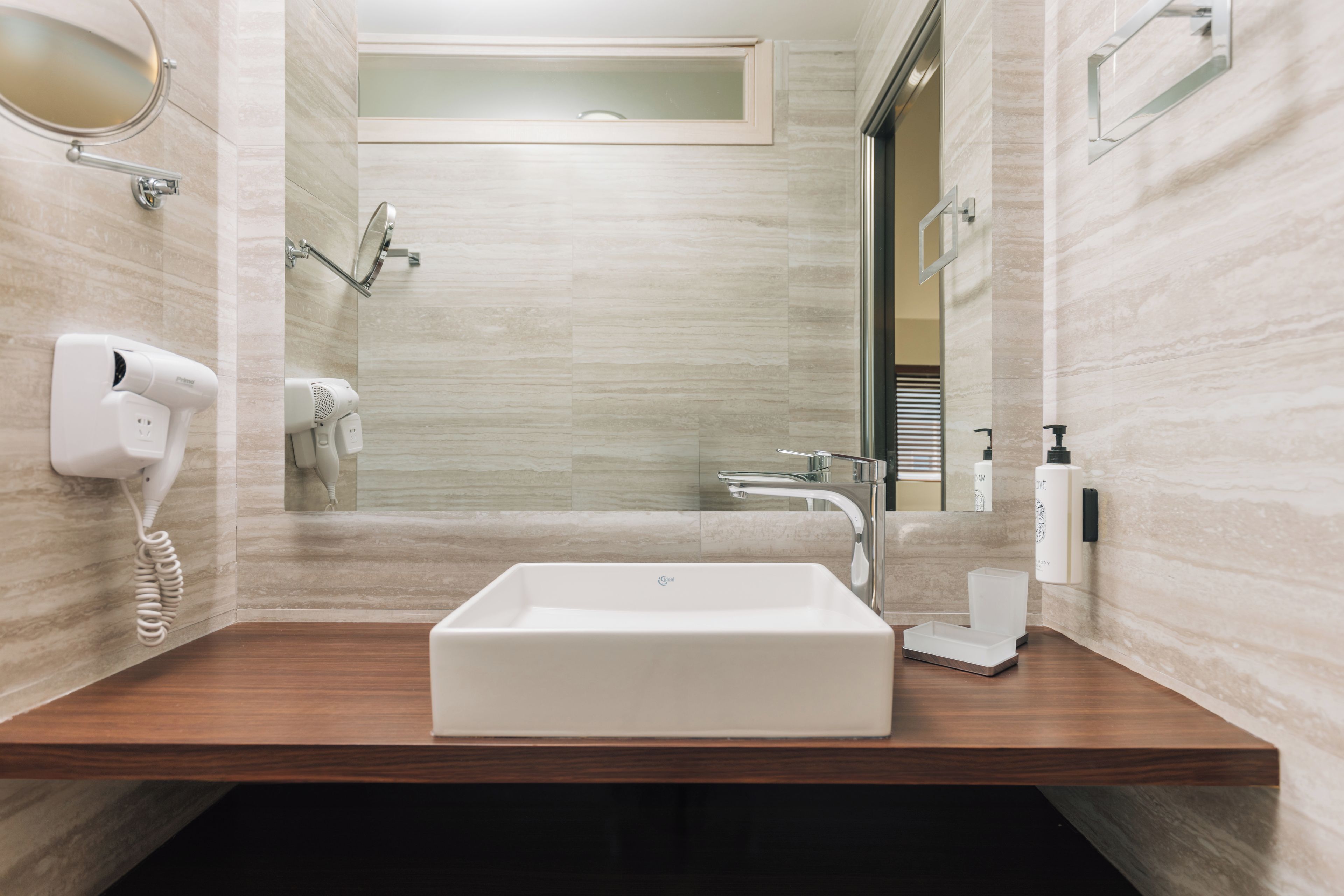 Une salle de bain moderne avec un lavabo rectangulaire, un sèche-cheveux et un miroir.