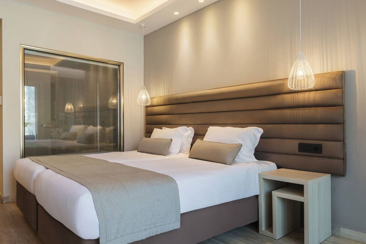 A modern bedroom with a large bed, bedside tables, and a glass partition.